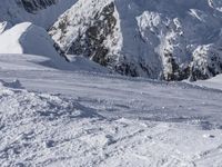 snow covered mountains and hills with a skier standing on the top of the hill, looking down