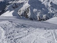 snow covered mountains and hills with a skier standing on the top of the hill, looking down