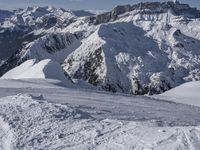 snow covered mountains and hills with a skier standing on the top of the hill, looking down