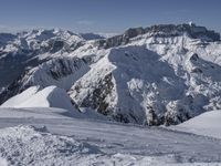 snow covered mountains and hills with a skier standing on the top of the hill, looking down