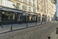 a stone city street lined with restaurants and shops with columns in front of buildings on the opposite side