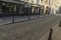 a stone city street lined with restaurants and shops with columns in front of buildings on the opposite side