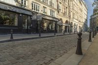 a stone city street lined with restaurants and shops with columns in front of buildings on the opposite side