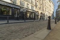 a stone city street lined with restaurants and shops with columns in front of buildings on the opposite side