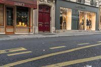 a man wearing jeans walks down the street and a yellow fire hydrant is in front of a shop