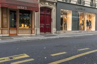 a man wearing jeans walks down the street and a yellow fire hydrant is in front of a shop