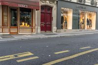 a man wearing jeans walks down the street and a yellow fire hydrant is in front of a shop