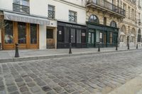 a street has some shops and buildings in the background with stone flooring on both sides