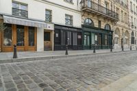 a street has some shops and buildings in the background with stone flooring on both sides