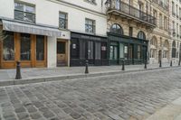 a street has some shops and buildings in the background with stone flooring on both sides