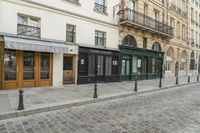 a street has some shops and buildings in the background with stone flooring on both sides