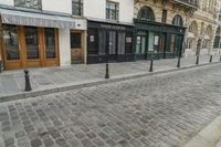 a street has some shops and buildings in the background with stone flooring on both sides