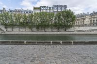 a bridge crossing over the water between buildings and a road leading to the canal or water that has a few cars passing by