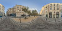 a street that has multiple buildings and a bench with people near it on the side