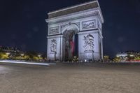 the arc de triopes with lights in the background in paris, france by night