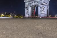 the arc de triopes with lights in the background in paris, france by night