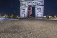 the arc de triopes with lights in the background in paris, france by night