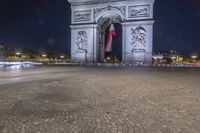 the arc de triopes with lights in the background in paris, france by night