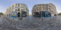 the 360 - view lens captures two city buildings on the opposite side of an intersection