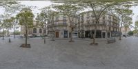 a very wide view of a building with trees on the side of the road and cars in the street