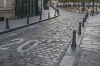 a cobble stone street has a bicycle lane in it on one side and a light post on the other