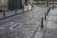 a cobble stone street has a bicycle lane in it on one side and a light post on the other