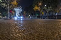 an empty street at night next to a tall building and a red traffic light on one side