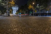 an empty street at night next to a tall building and a red traffic light on one side