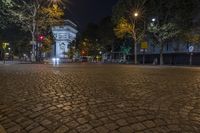 an empty street at night next to a tall building and a red traffic light on one side