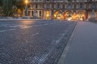 an empty road with cars driving down it at dusk in the middle of a big city