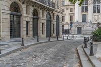 an image of a building that has cobblestones and stairs on it and the street is lined with trees