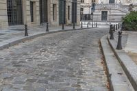 an image of a building that has cobblestones and stairs on it and the street is lined with trees