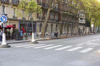 a crosswalk on the street near buildings and motorcycles behind it and people outside the building