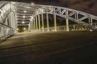 a large bridge with a man walking across it at night time in the city with some lights
