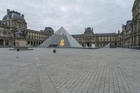 the large pyramid is in a courtyard between two buildings and an empty path leading into it