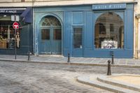 a street corner with a blue building and a stop sign in front of it in paris