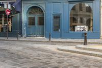 a street corner with a blue building and a stop sign in front of it in paris