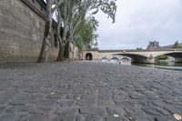 the walkway between two bridges is set along a river in paris, france, on a cloudy day