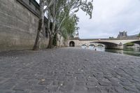 the walkway between two bridges is set along a river in paris, france, on a cloudy day