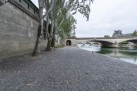 the walkway between two bridges is set along a river in paris, france, on a cloudy day