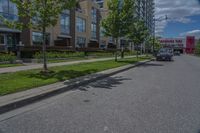 parked cars are on the street next to the houses and trees and a blue sky with white clouds