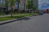 parked cars are on the street next to the houses and trees and a blue sky with white clouds