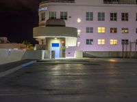 a parking lot with an entrance lit up at night in an apartment complex that also serves as a parking garage