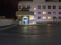 a parking lot with an entrance lit up at night in an apartment complex that also serves as a parking garage