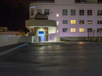 a parking lot with an entrance lit up at night in an apartment complex that also serves as a parking garage