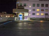 a parking lot with an entrance lit up at night in an apartment complex that also serves as a parking garage