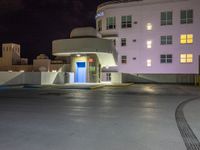 a parking lot with an entrance lit up at night in an apartment complex that also serves as a parking garage