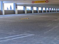 an empty parking garage with two rows of empty cars in it, and several white pillars