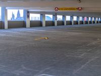 an empty parking garage with two rows of empty cars in it, and several white pillars