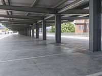 a parking garage with columns and a tiled floor, as seen from the walkway of another building